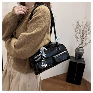 Detail of black patent leather shoulder bag with heart charms and ribbon decorations