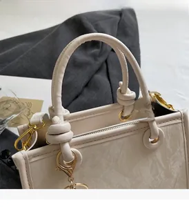 Détail d'un sac à main en cuir crème texturé avec anses nouées et garnitures dorées