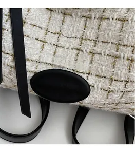 Detail showing white tweed fabric with gold threads and black leather strap textures