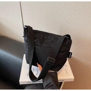 Détail du sac seau noir en nylon plissé avec bandoulière réglable et étiquette logo