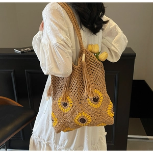Close-up of bohemian woven straw bag with handmade sunflower crochet details and tassels