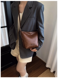 Close-up of deep brown woven bucket bag featuring premium leather texture and crossbody strap