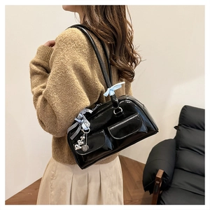 Detail of black patent leather bag featuring blue satin bow and heart-shaped charms
