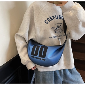 Detail view of blue nylon crescent crossbody bag with street style graphic print on model