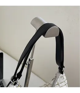 Close-up of smooth black faux leather shoulder strap with silver metal buckle detail