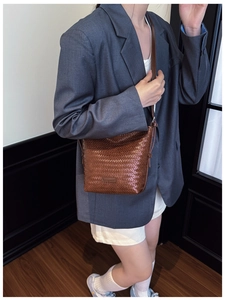 Close-up of brown woven leather texture on a stylish crossbody bucket bag for women