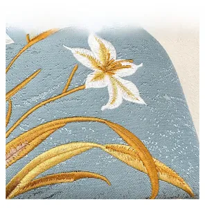 Close-up of light blue jacquard fabric with white and gold floral embroidery detail