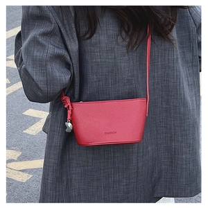Detail of red pebbled leather bucket bag with silver heart charm and fashion logo