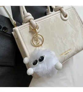 Détail d'un porte-clé peluche blanc avec lunettes sur un sac à main motif marbre