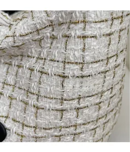 Macro detail of elegant tweed fabric with gold thread weaving on a versatile tote bag