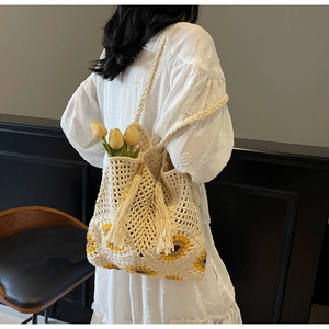Macro detail of hand-woven crochet tote bag with sunflower pattern and fringe tassel