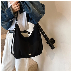Close-up of a large black nylon tote bag with silver metal plate and side drawstring