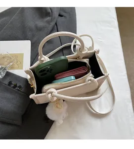 Vue de dessus du mini sac cabas crème montrant l'espace intérieur avec téléphone et bijou