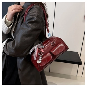 Detail of burgundy glossy leather bowling bag featuring decorative lace bows and heart charms
