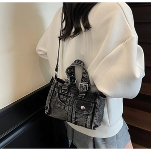 Detail of a black denim crossbody bag with vintage metal buckles and cargo pockets