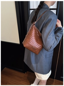 Brown woven bucket bag shown with a grey blazer for a modern minimalist style