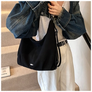 Detail of a large black hobo shoulder bag with matte texture and oval silver metal buckle