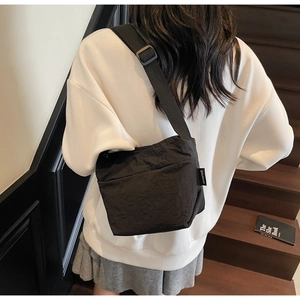 Borsa a tracolla minimalista in nylon nero con etichetta del marchio indossata da modella