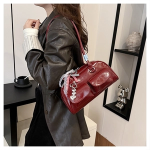 Detail of burgundy glossy leather underarm bag featuring lace bows and heart charms