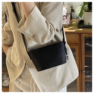 Detail of black lychee grain leather bucket bag with FASHION logo and thin shoulder strap
