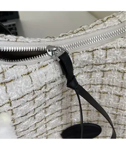 Detailed macro shot of white tweed fabric texture and a long leather zipper pull