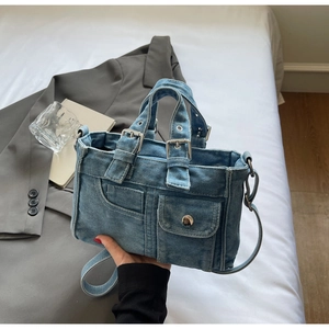 Detailed close-up of blue denim handbag with functional pockets and silver hardware