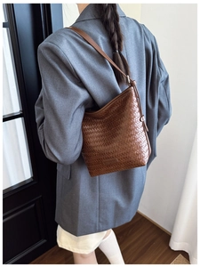 Detail of brown woven bucket bag in herringbone faux leather with a minimalist strap