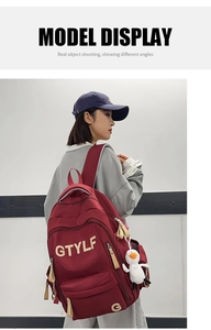 Side view of a burgundy large capacity backpack with a white duck plush charm on a model