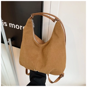 Detail of a brown suede hobo bag featuring silver zippers and matte vintage texture