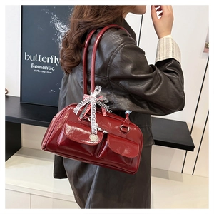 Detail view of burgundy leather bowling bag with lace bows and heart charms on model