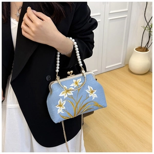 Detail of light blue embroidered handbag with white lilies and pearl handle for women