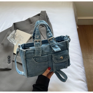 Detail of vintage denim tote bag with external utility pockets and metal hardware