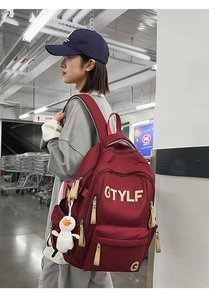 Detail of burgundy student backpack featuring white duck plush toy and GTYLF logo print