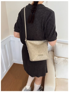Chic beige woven bucket bag shown on a model for a stylish crossbody and shoulder look
