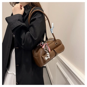 Detail of dark brown leather bowling bag featuring front pockets and decorative bow charms