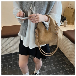 Detail of a brown suede hobo bag featuring decorative thick rope knot shoulder strap details