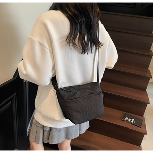 Détail de la bandoulière réglable et du logo sur un sac seau noir en nylon texturé