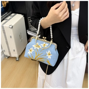 Close-up of vintage blue embroidered floral bag with pearl handle and metal chain