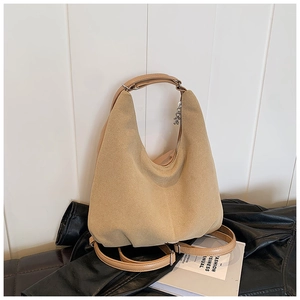 Detail of minimalist beige suede convertible tote bag with metal buckles on fashion magazine