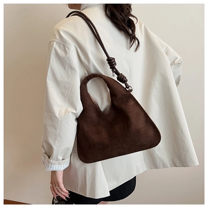 Detailed close-up of dark brown suede shoulder bag with unique knotted strap design