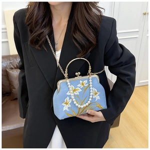 Detailed view of light blue silk embroidery bag with gold clasp and pearl handle strap