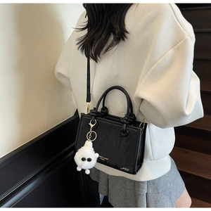 Close-up of black leather leopard bucket bag featuring gold hardware and plush charm