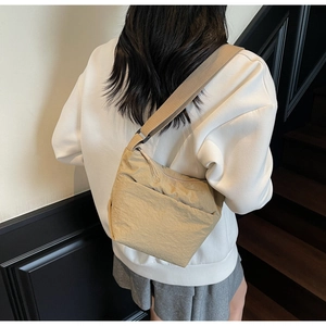 Detail of beige wrinkled nylon crossbody bag with adjustable wide shoulder strap on a model