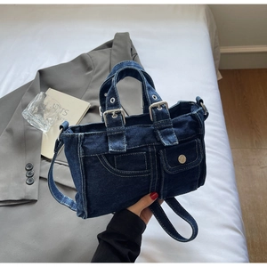 Close-up of deep blue denim handbag with functional pockets and silver metal hardware details