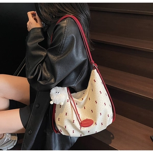 Detail of canvas half-moon shoulder bag with red bow print and plush chicken pendant