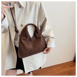 Detail showing the fine texture and drape of this dark brown suede hobo bag on a model