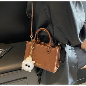 Detail of a brown marble texture bucket bag with a cute plush sheep charm on a leather coat