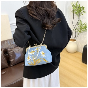Detailed view of light blue floral embroidery on fabric bag with pearl handle