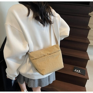 Sac bandoulière minimaliste kaki porté par un mannequin dans un décor d'escalier