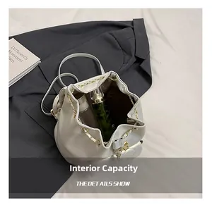 Internal capacity of bucket bag showing perfume and phone with gold chain details